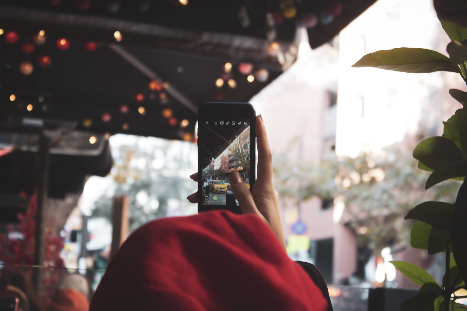 A person standing on street , holding a phone and looking at Instagram stories on the screen.