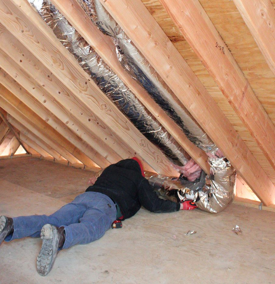 Man laying in attic installing HVAC ducts