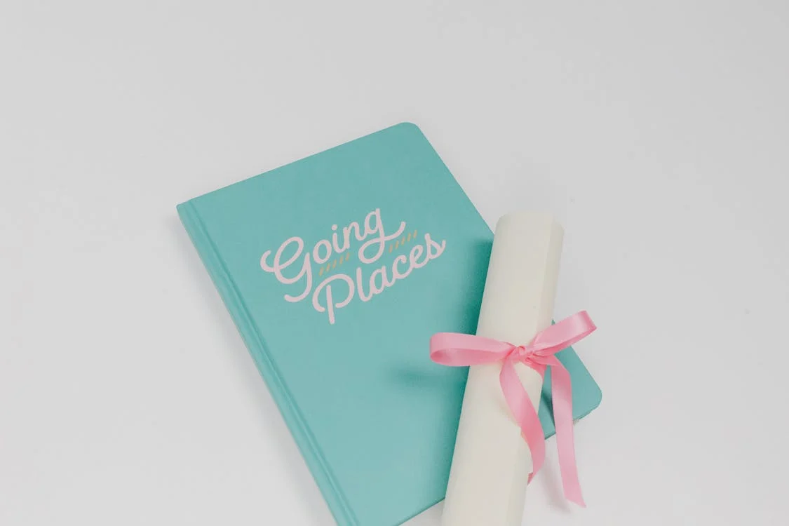 Photo by Tara Winstead: https://www.pexels.com/photo/green-notebook-and-white-rolled-paper-with-pink-ribbon-7723789/ 