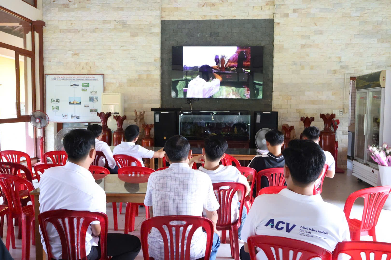 A group of people sitting in a room watching a televisionAI-generated content may be incorrect.