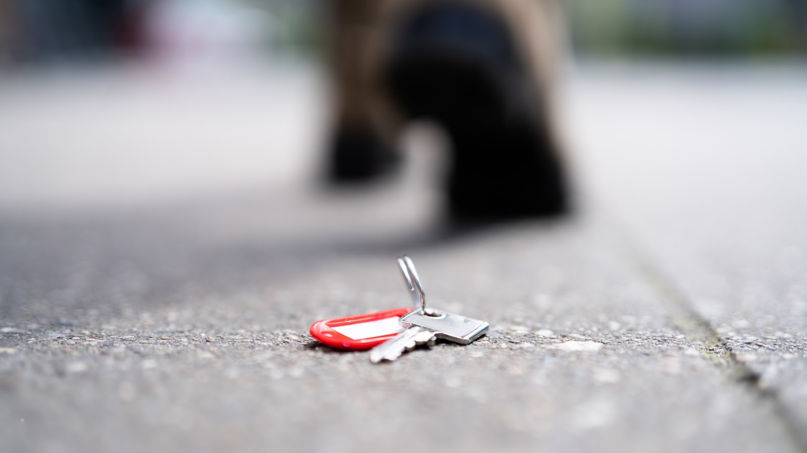 Dropped house keys on the ground, emphasizing the need for lock replacement after losing keys.