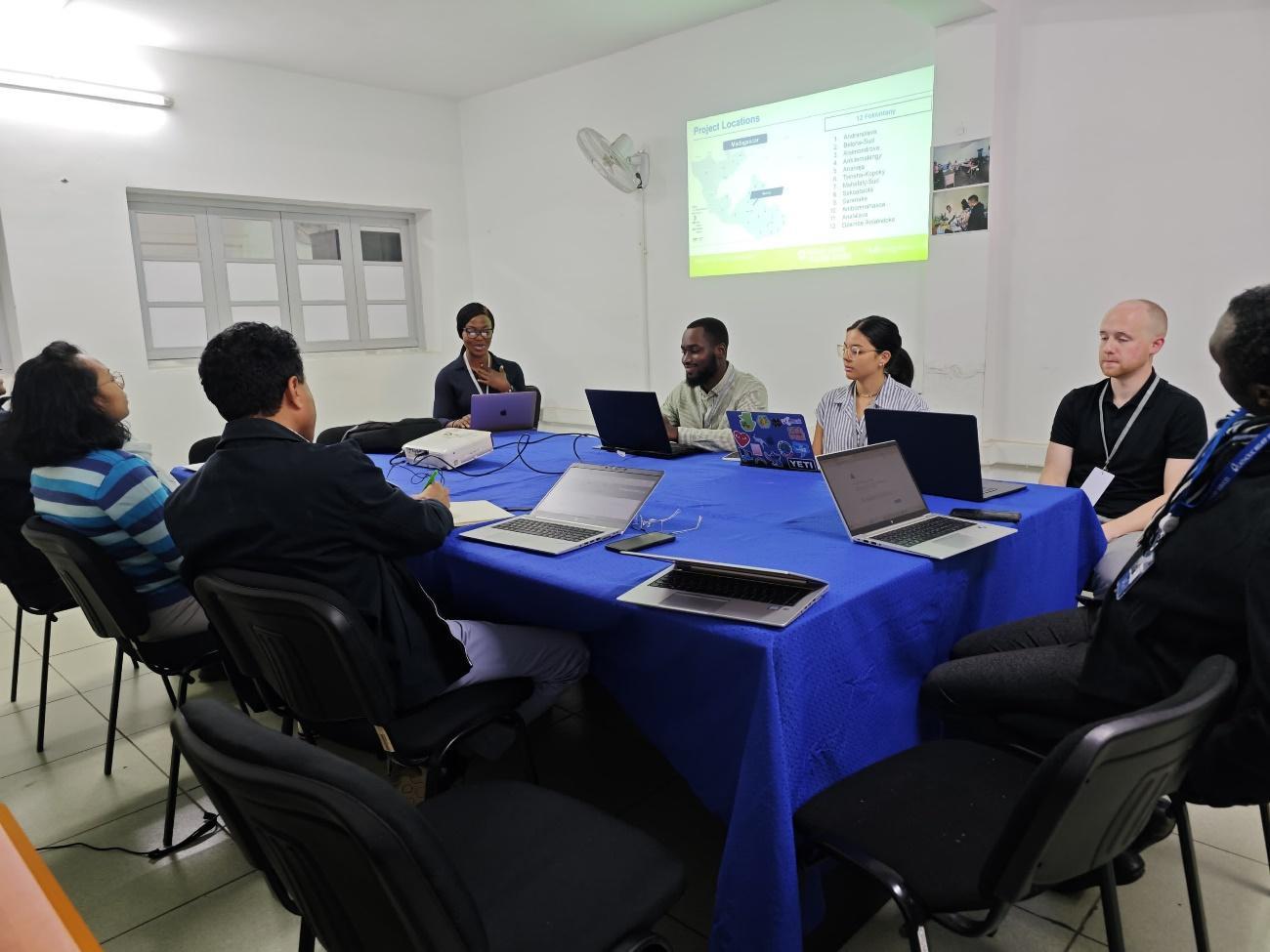 A group of people sitting around a table with laptops

Description automatically generated