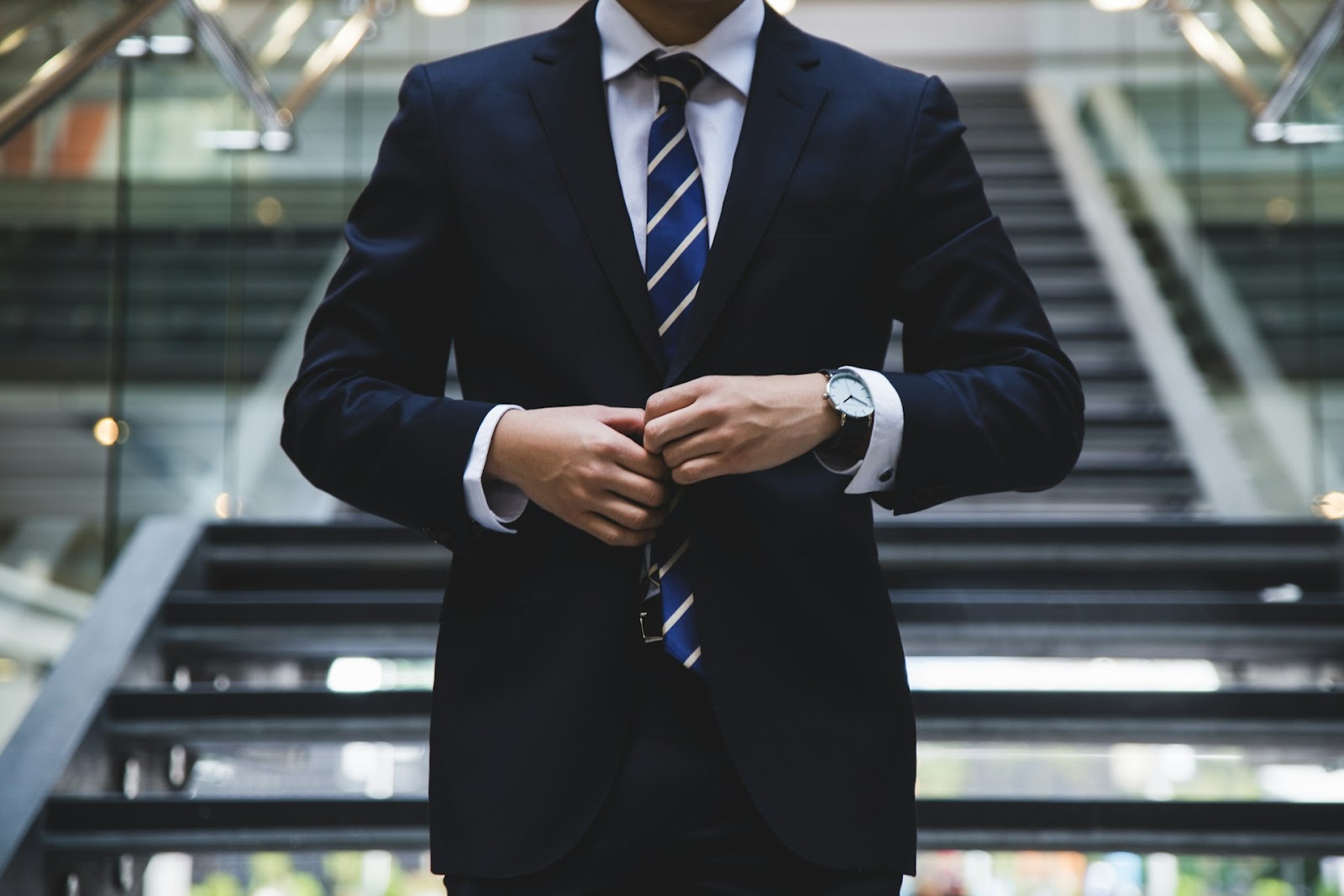 A man in a sharp suit and tie stands confidently