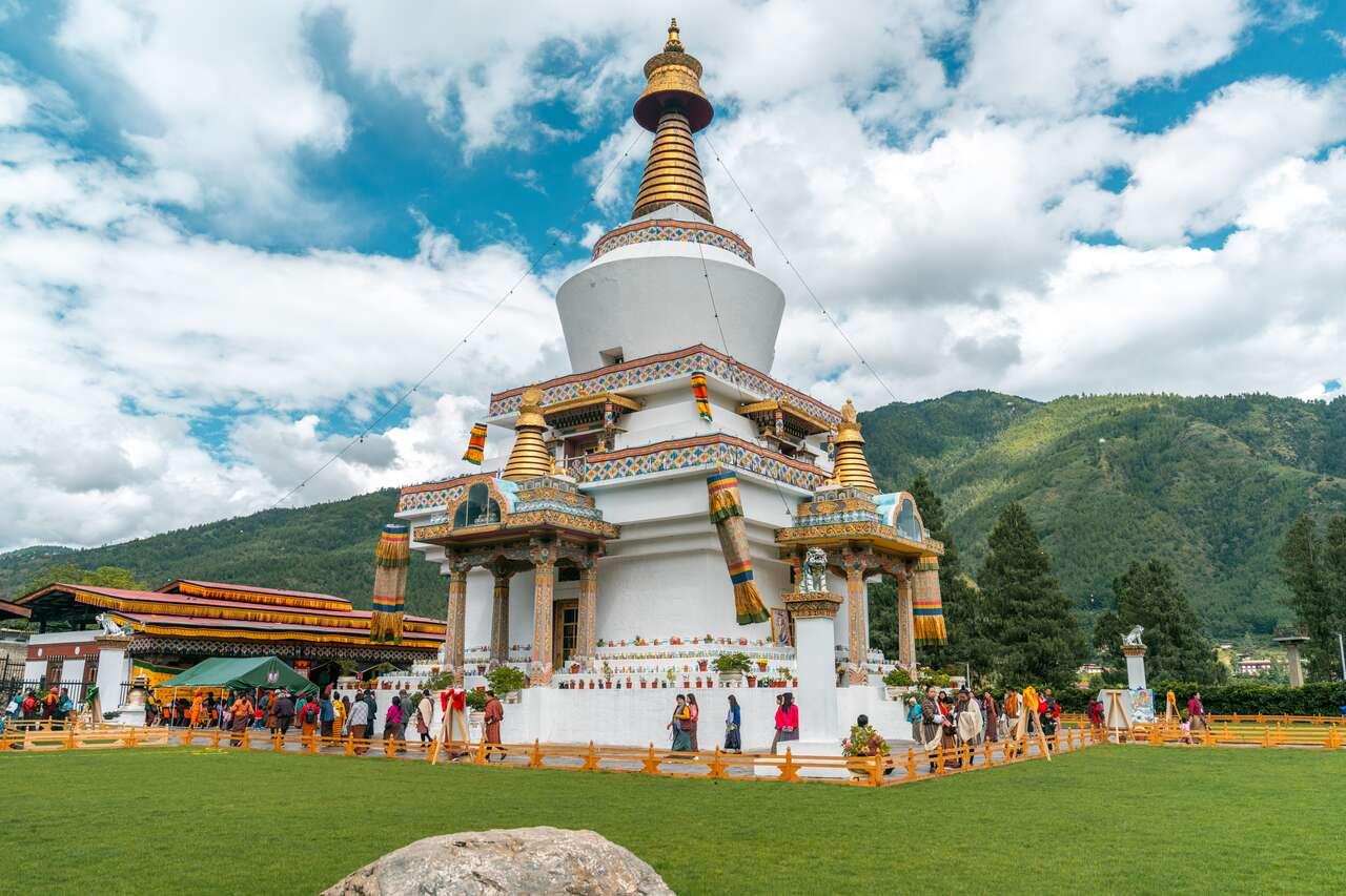 A white building with a tower and people in front of itDescription automatically generated