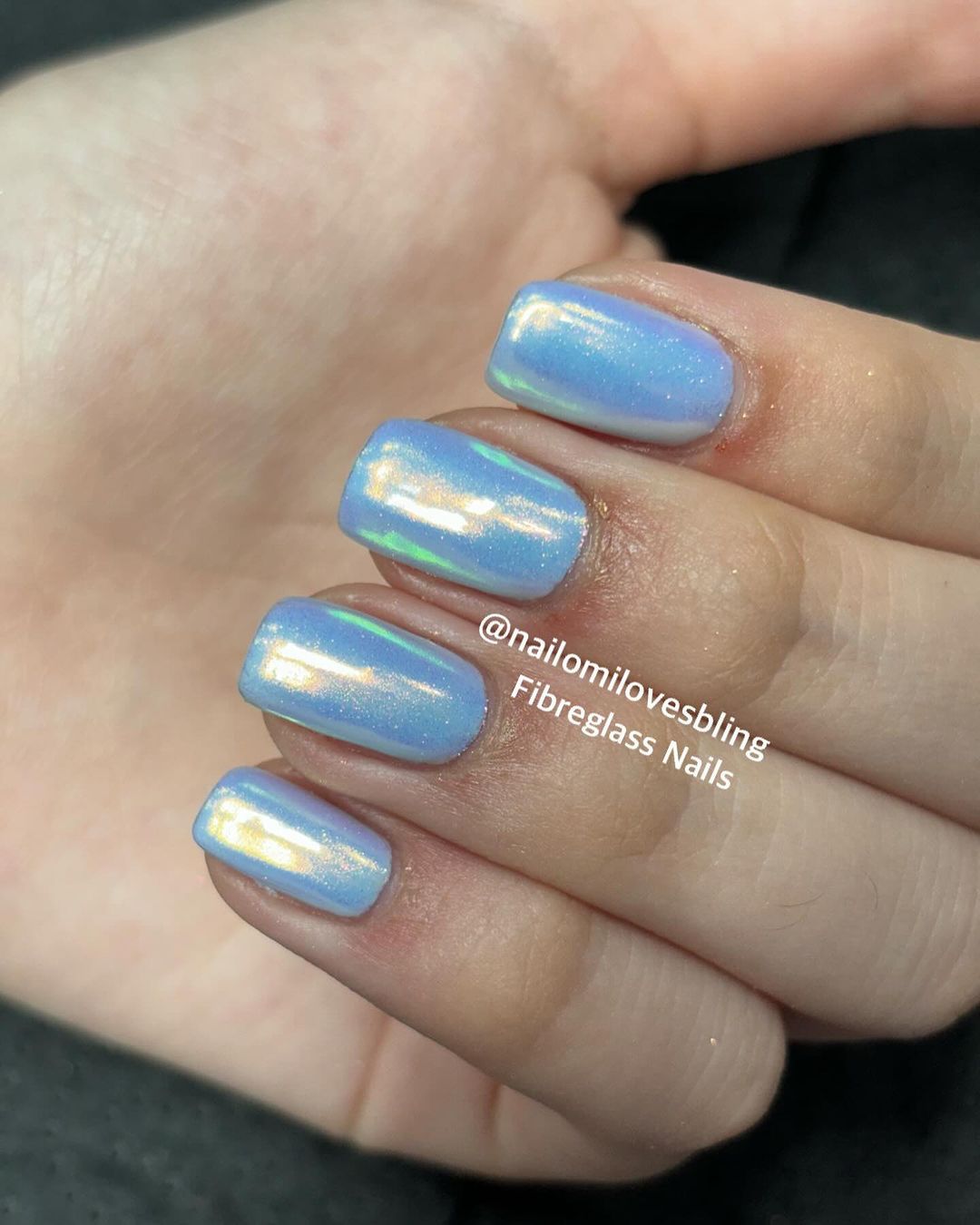 Close up of hands with blue winter nails having Short shiny nail art