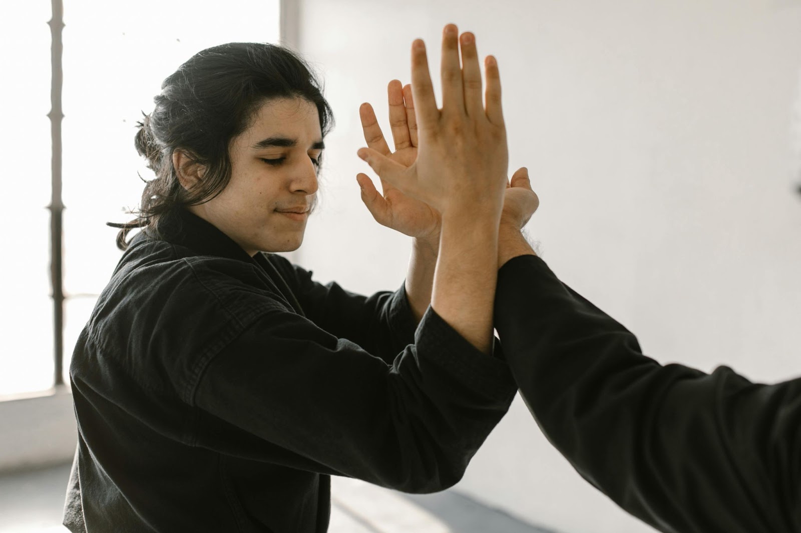 Two martial arts practitioners facing each other, performing a move with their arms interlocked. 