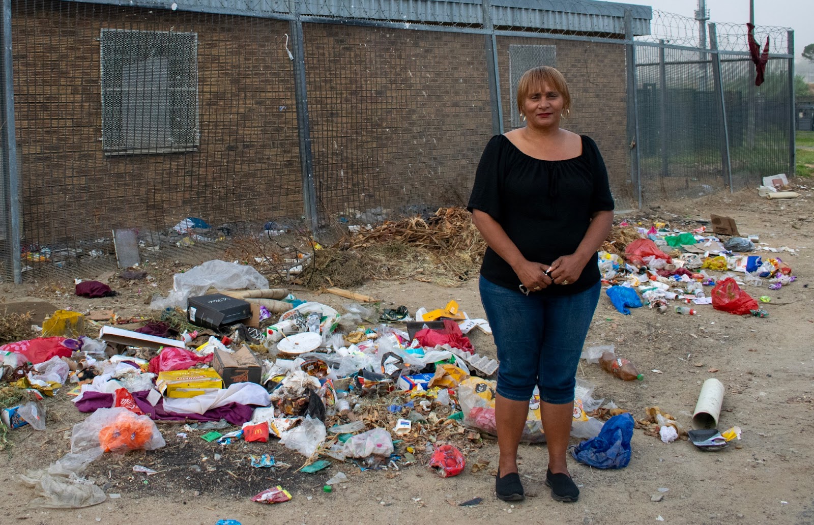 Sonja Adonis standing near a pile of litter in Cloetesville.