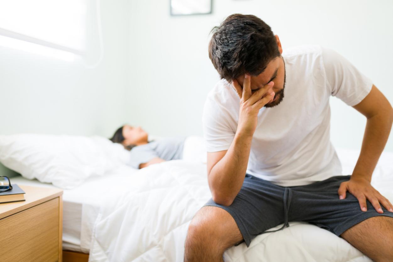 thoughtful-young-man-pjs-sitting-up-bed-morning-feeling-sad-with-his-bad-relationship