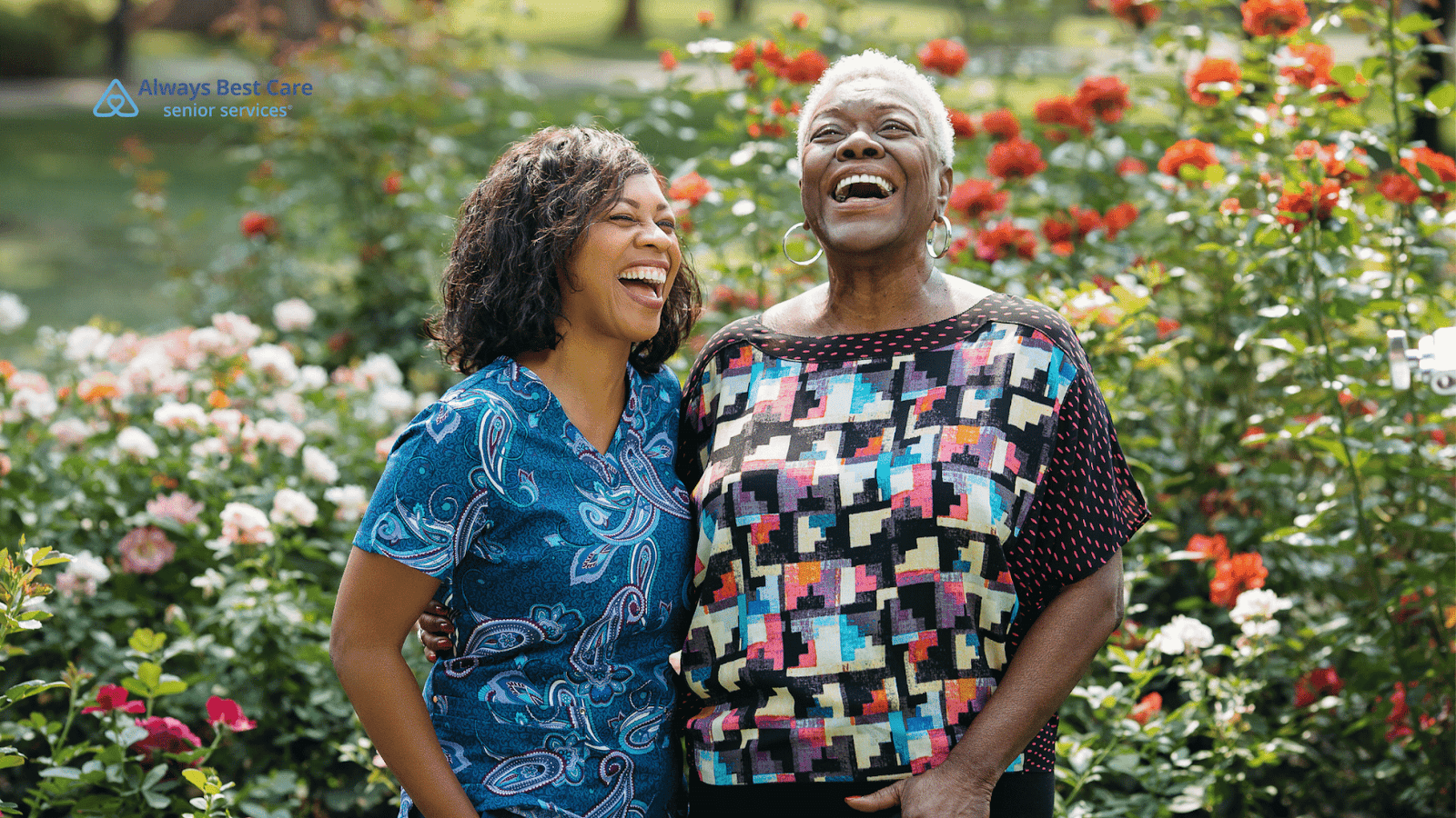 This image depicts a senior woman and a female caregiver in a garden smiling