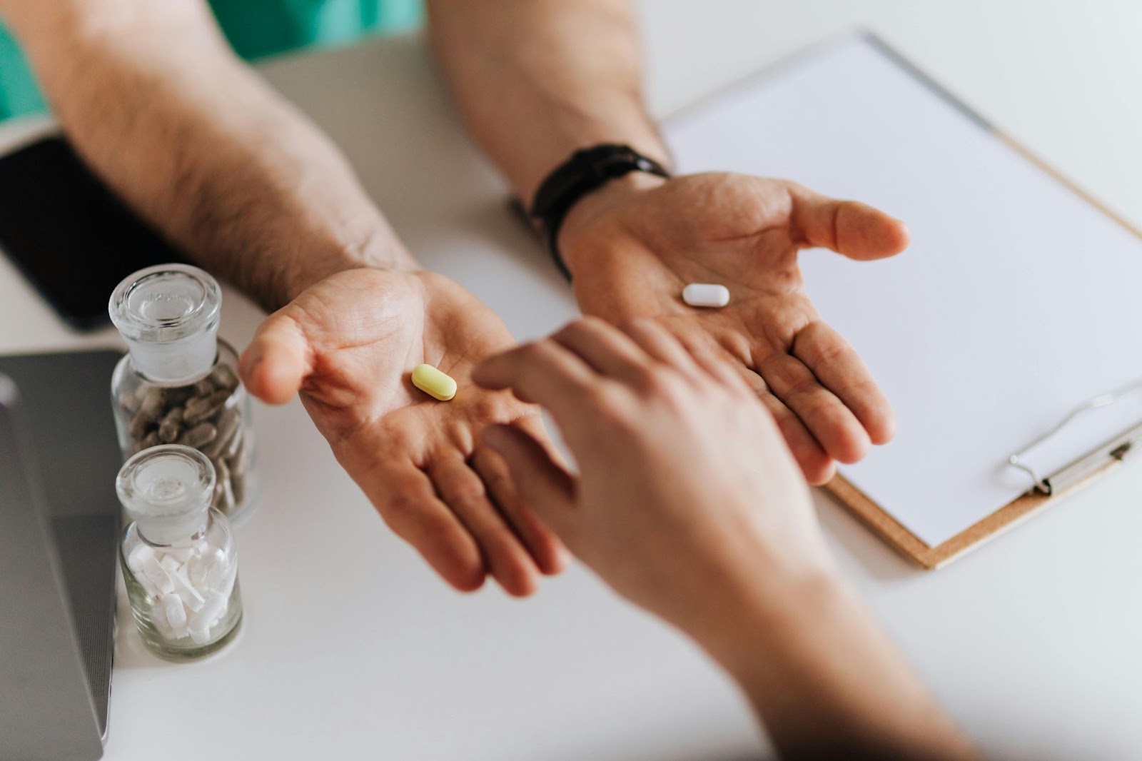 Person holding two pills in open palms, while another chooses one.