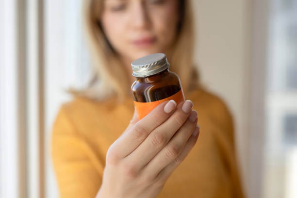 A woman carefully reading the label on a bottle of multivitamins, highlighting the importance of informed supplement choices.