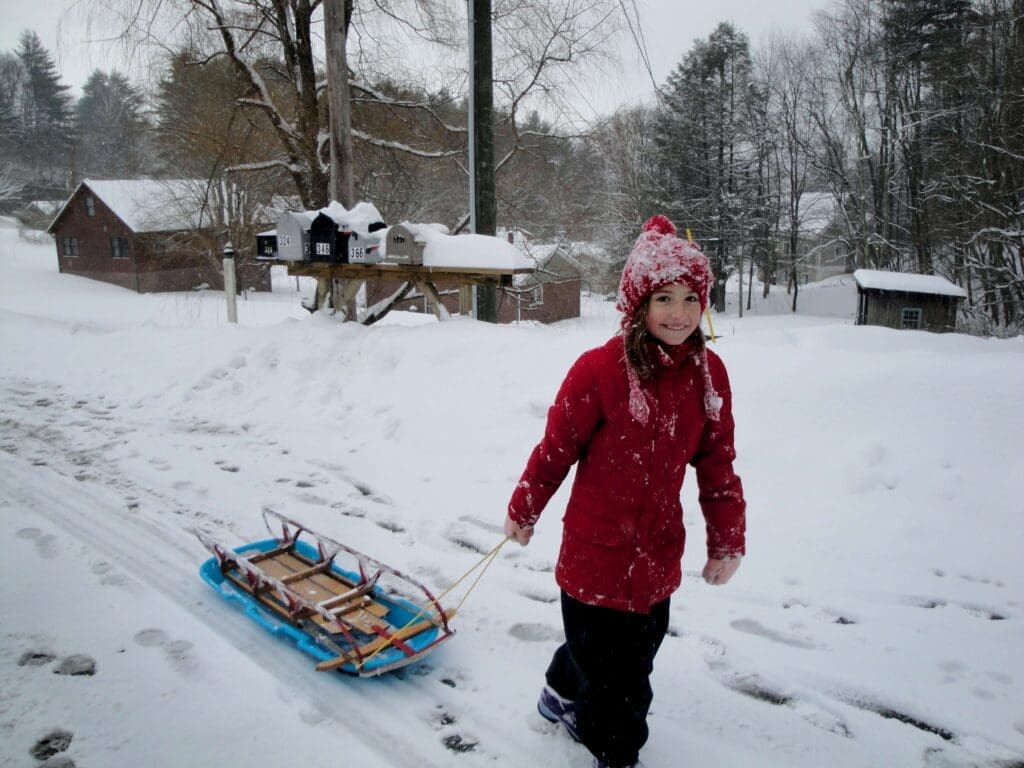 A child pulling a sled in a car-free resort in the Alps