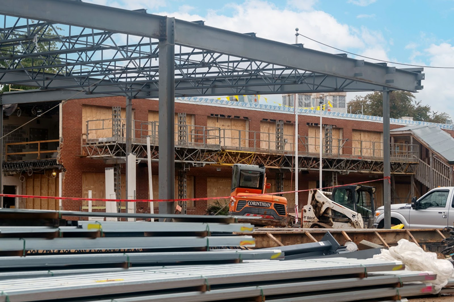 School under construction with exposed steel beams and bulldozers. 