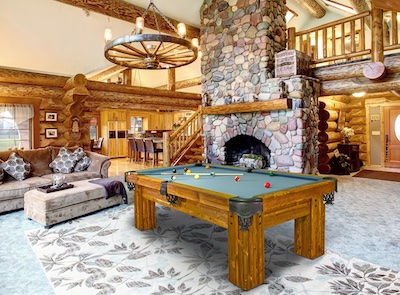 A rustic pool table in the middle of a ski lodge living room.