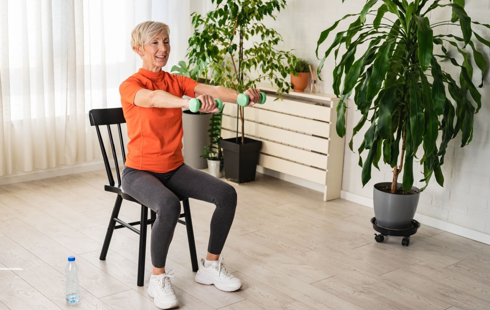 A senior performs a weight lifting exercise while sitting in a chair to avoid putting stress on their joints.