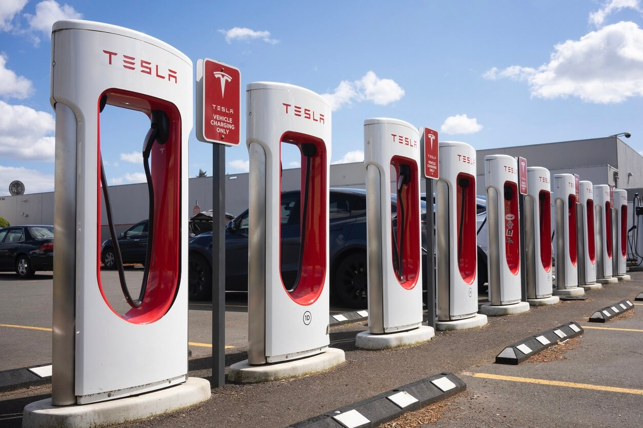  PNG  Row of Tesla chargers with signs in parking lot.
