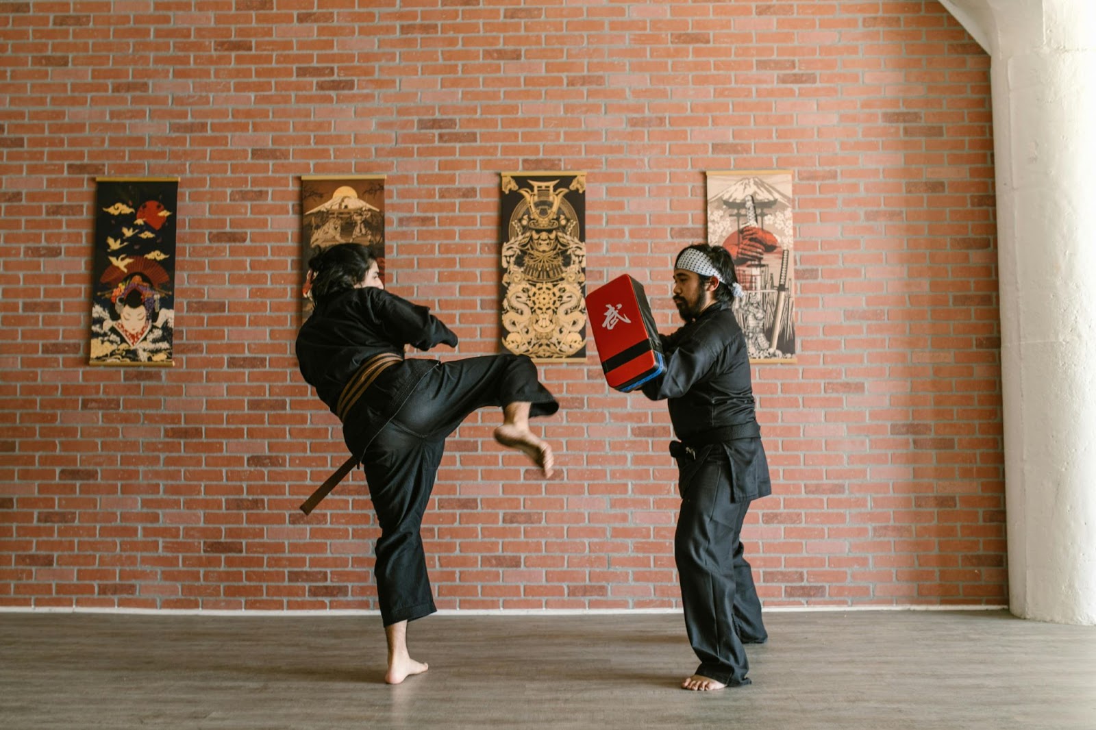 A martial arts students practicing kicks with her instructor