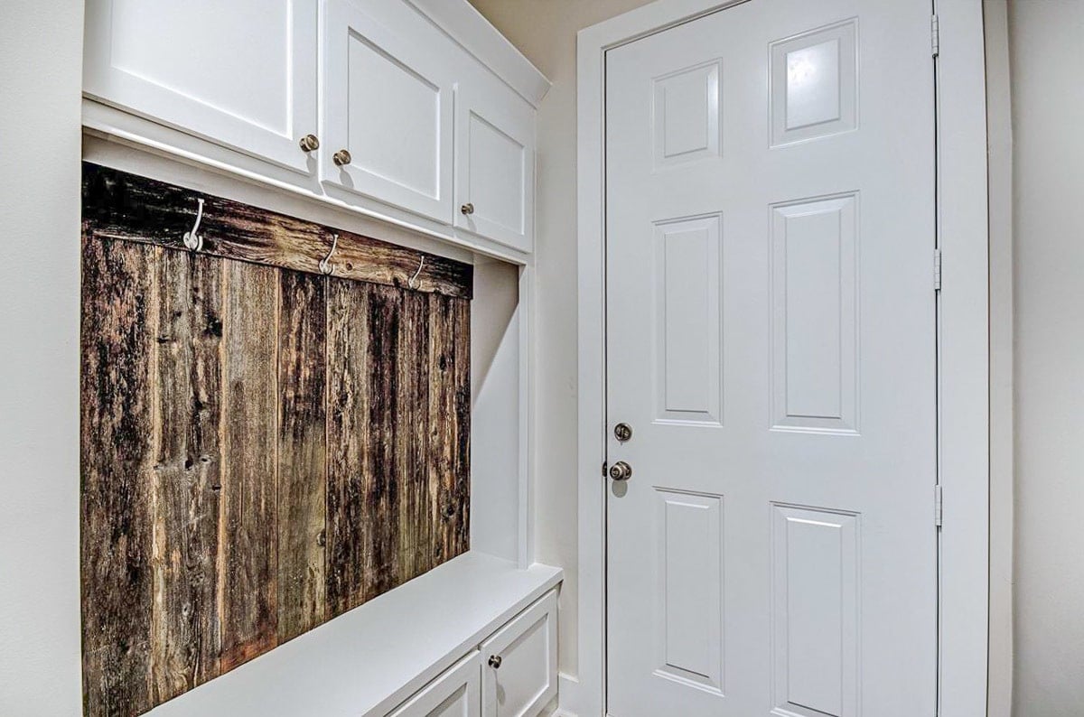 Mudroom with a coat rack, white cabinets, and a built-in bench.
