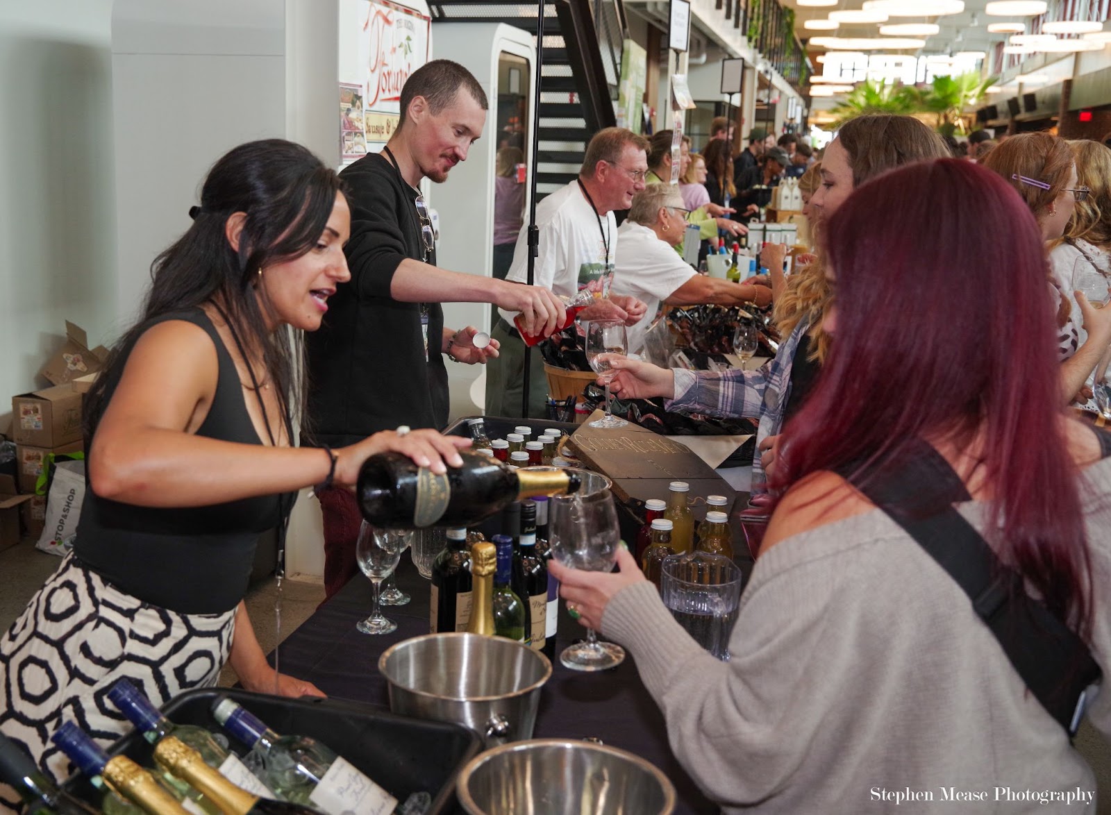 People pouring wine to attendees at the 2024 Burlington Food & Wine Festival at Hula.