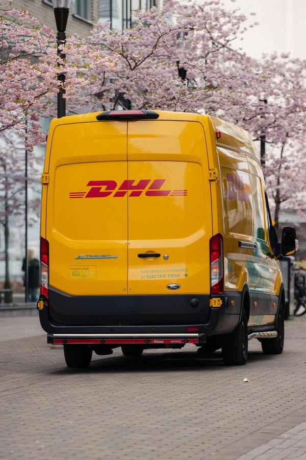 DHL van making a street delivery at a local pick-up point, highlighting last-mile logistics and accessible shipping solutions.