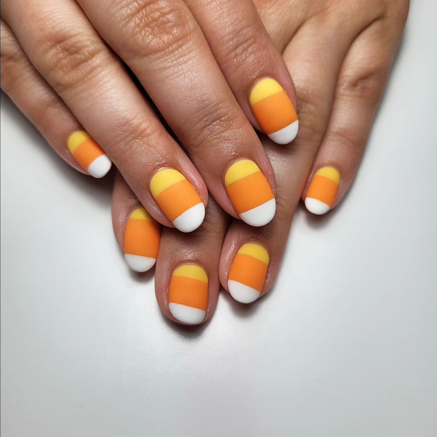 Close-up of hands with fall nail design having Candy Corn-Inspired Color Blocking