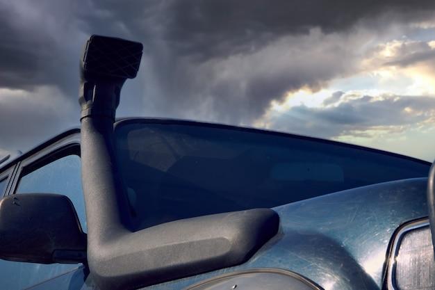 A snorkel mounted on a 4x4 SUV against a stormy sky. The concept of adventure travel.