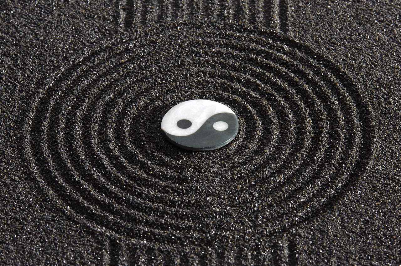 A Yin Yang symbol in the middle of Zen garden with black sand. 