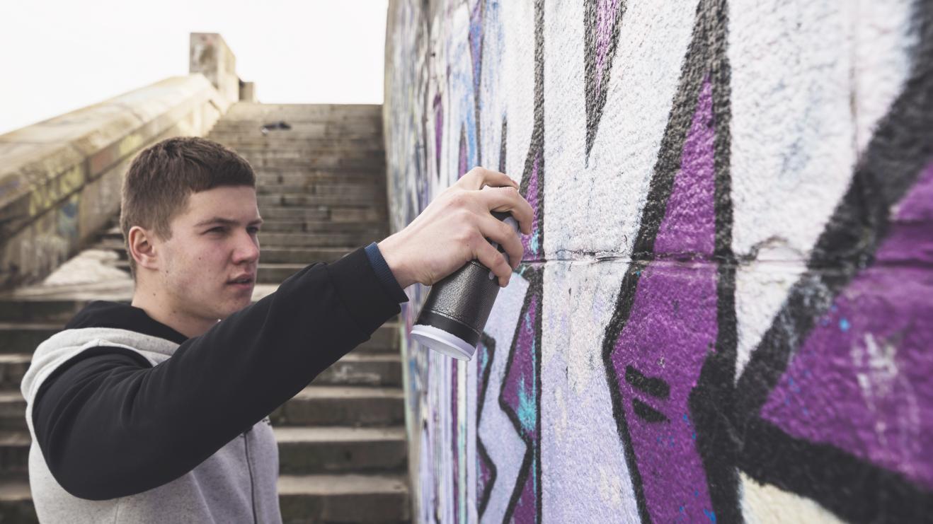 young-artist-drawing-colorful-graffiti-wall