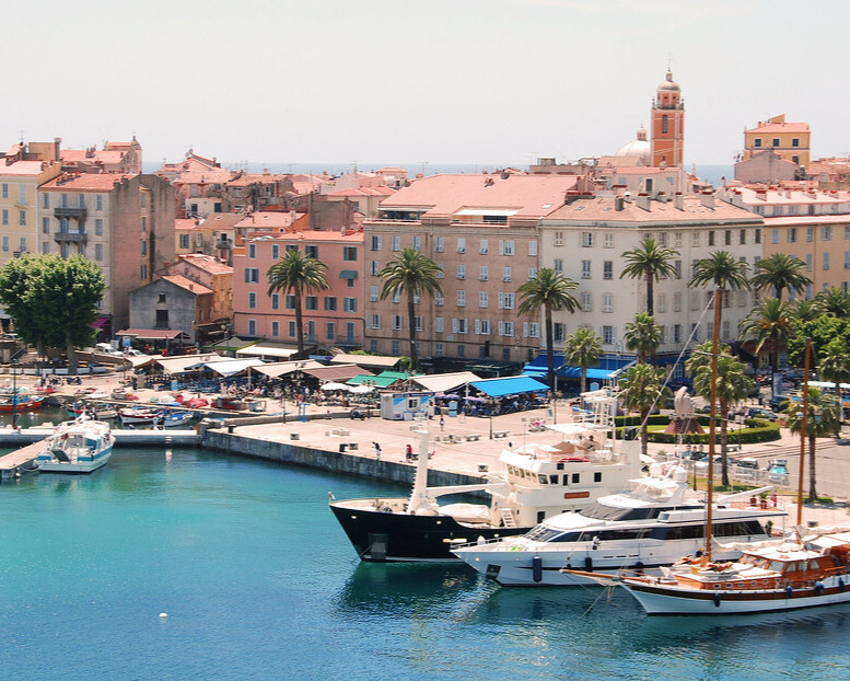 Corsica coastline with water, boats, and buildings.