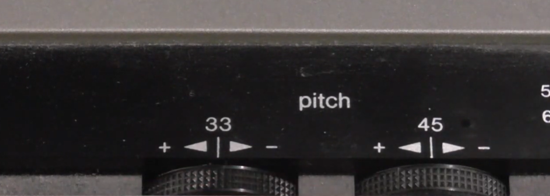 Close-up of turntable pitch control dials showing speed adjustment options for 33 and 45 RPM settings.