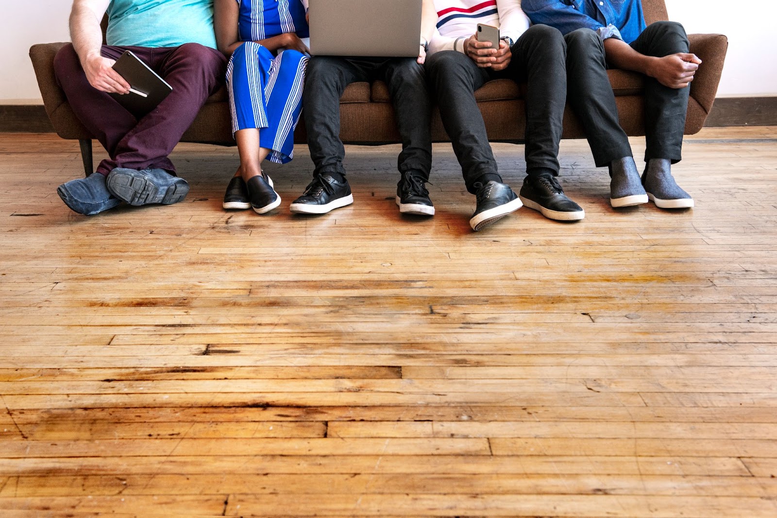 Friends sitting in a room with hardwood flooring on a couch.