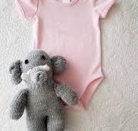 A baby clothes and a stuffed elephant Description automatically generated