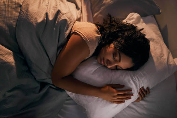 A woman peacefully sleeping in bed, looking well-rested after taking magnesium and melatonin for better sleep.