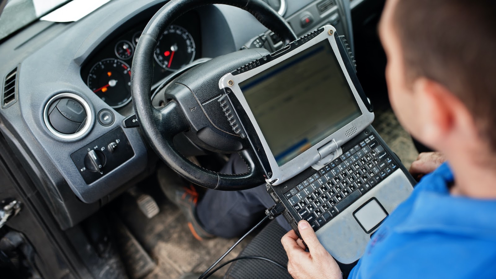 A locksmith is programming a smart car key inside a vehicle.