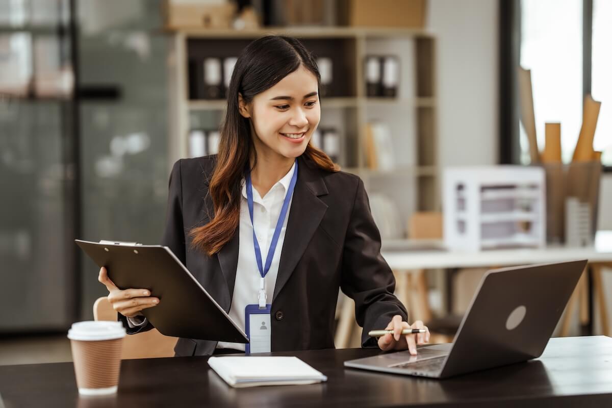 Continuous performance management: HR manager using a laptop while holding a clipboard