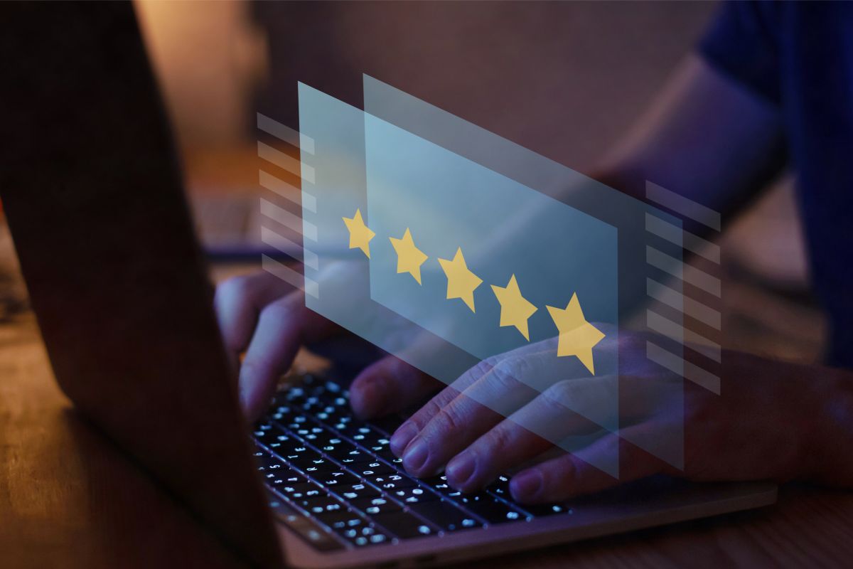 a person typing on a laptop with five stars on the screen