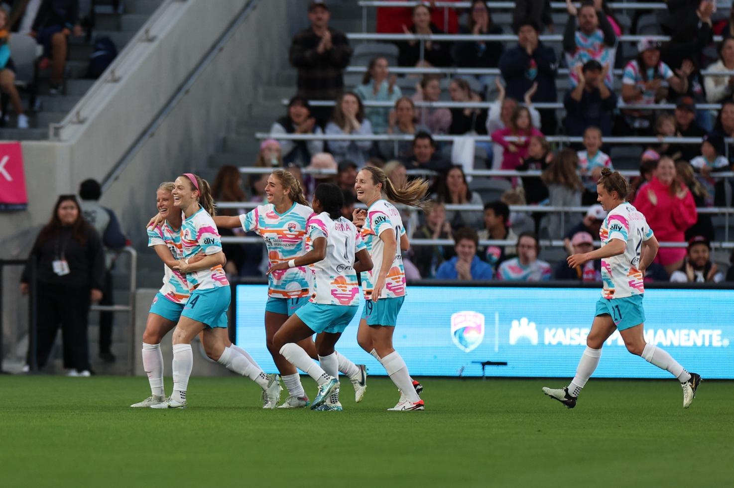 A group of women's football players running on a field Description automatically generated