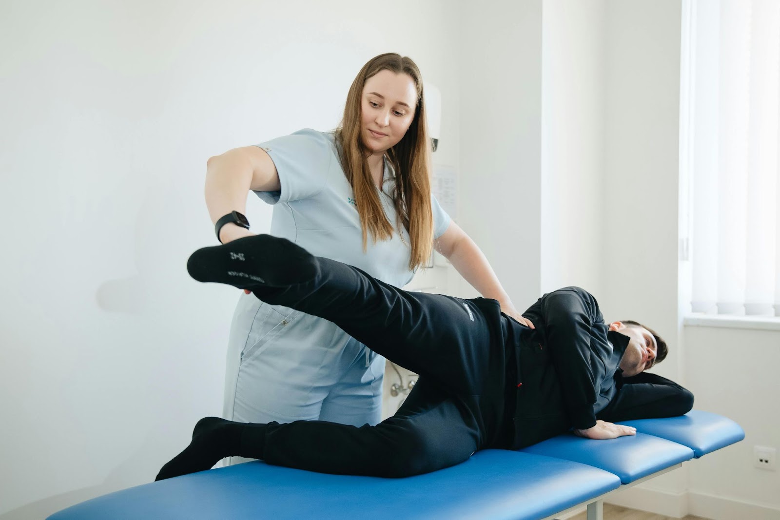 A physical therapist helps a patient with a leg exercise.