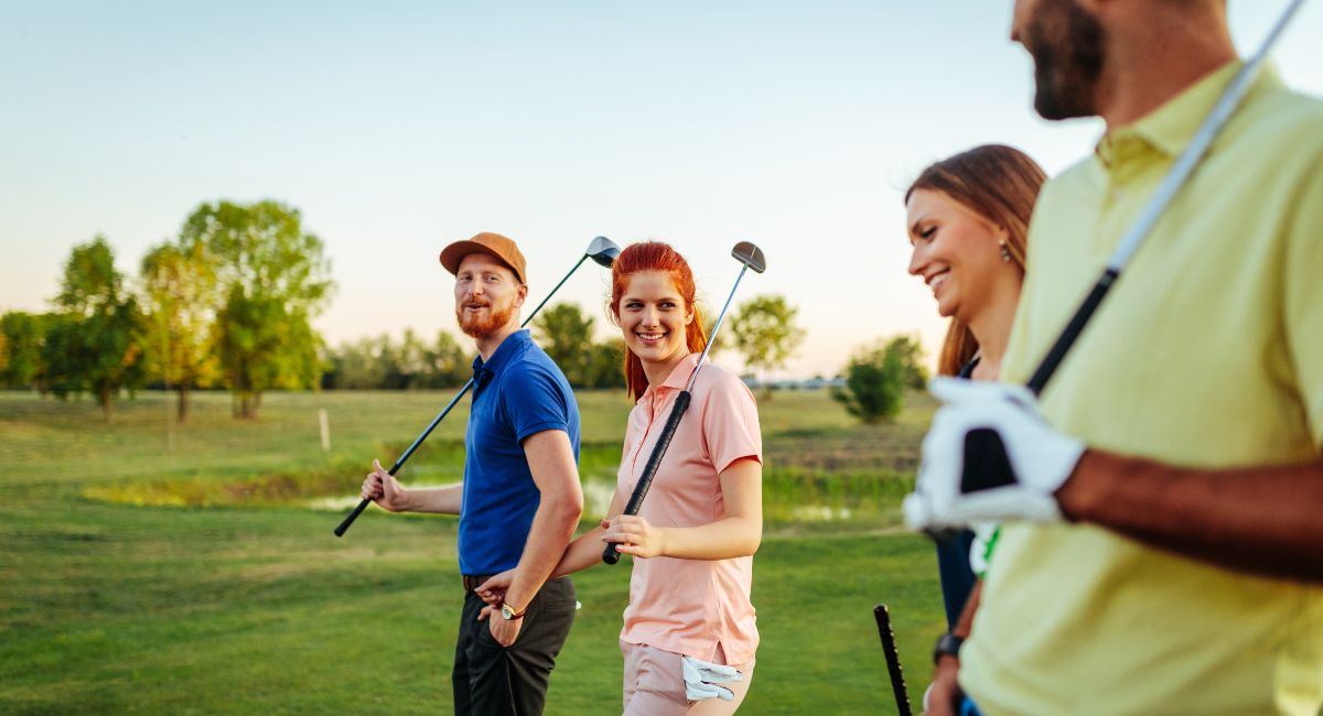 Group of young adults smiling and walking with golf clubs on a sunny day at Gearhart Golf Links—one of the oldest golf courses on the Oregon Coast, perfect for social and recreational golf experiences