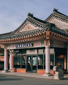 This contains an image of  starbucks coffee shop at the corner of a street in front of a chinese building