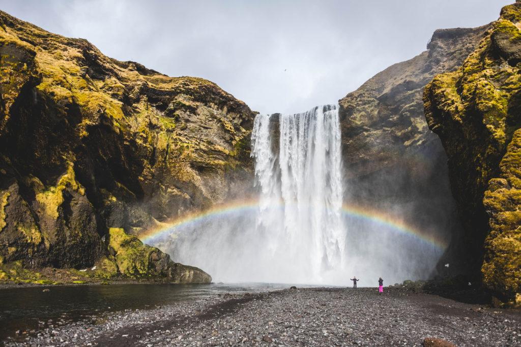 people excited by the waterfall and rainbow