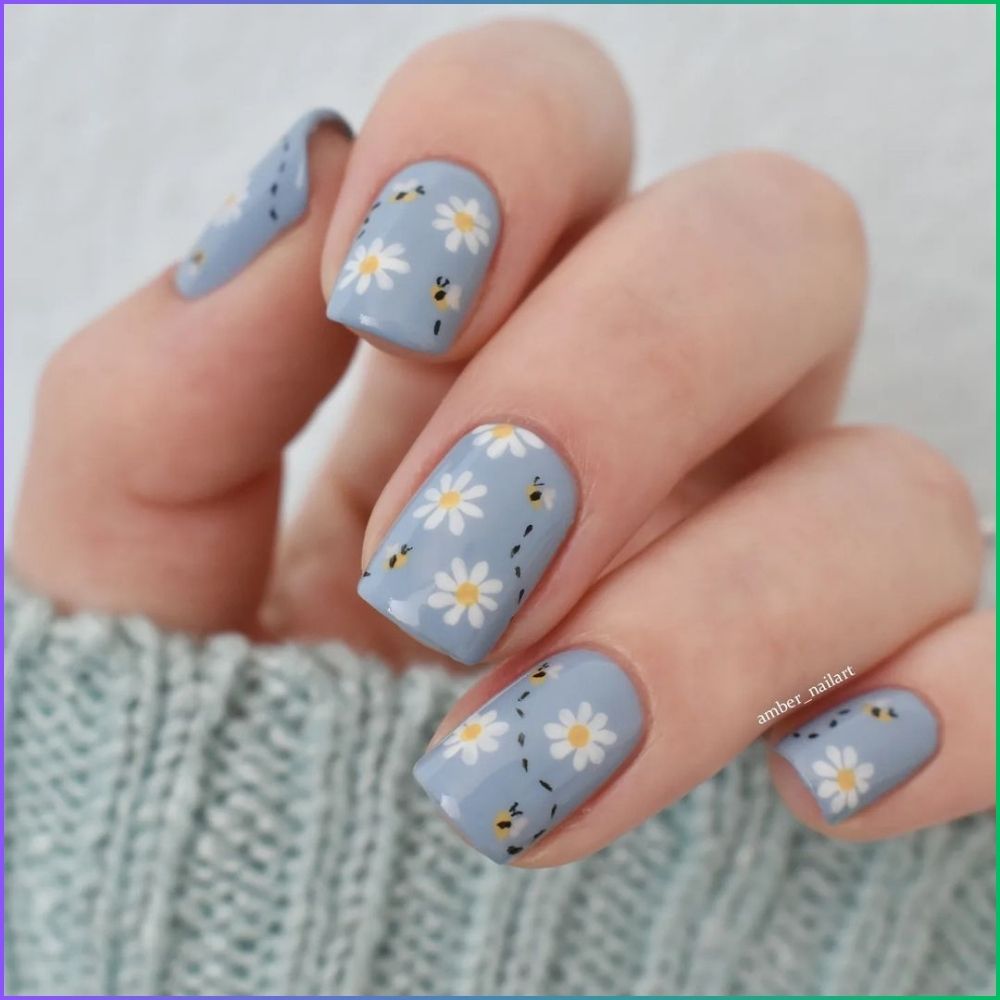 Close up of hands with flowered designed blue nails having Busy Bee Beauty