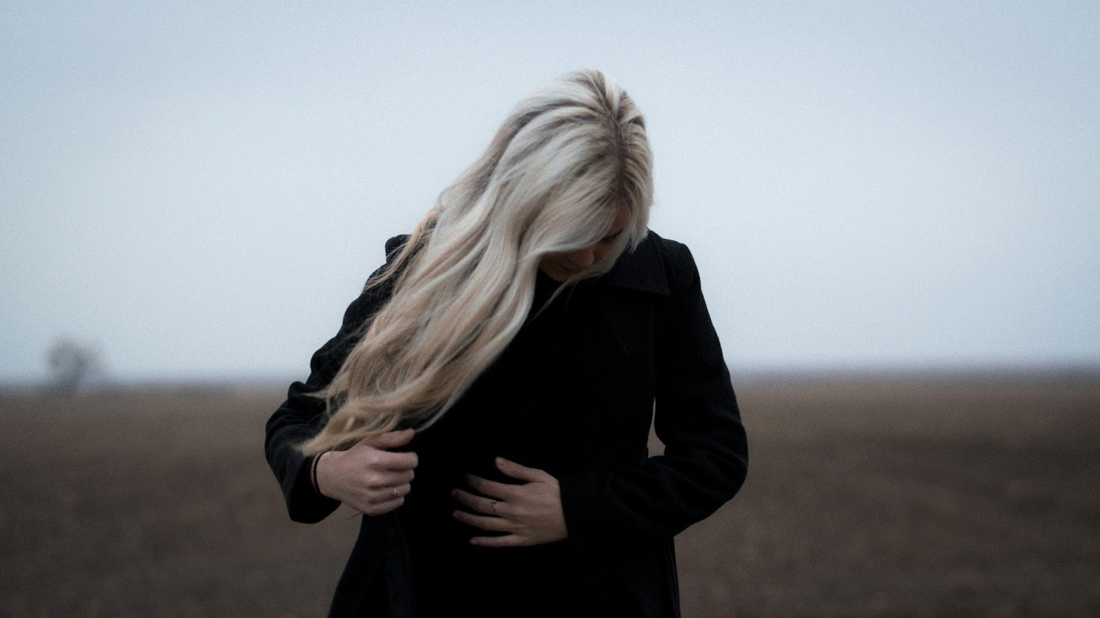 Woman outdoors with long, wavy platinum blonde clip-in extensions