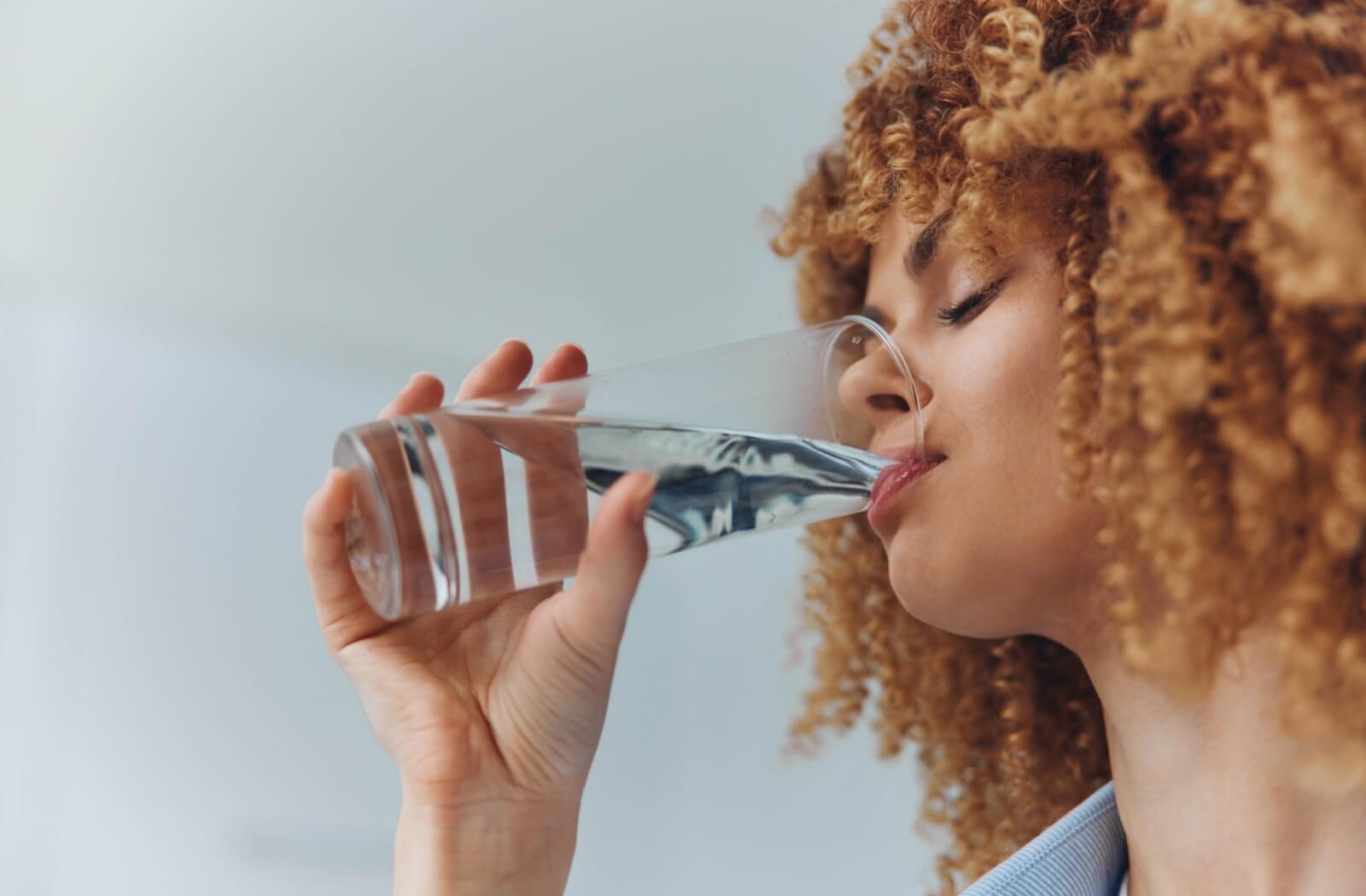 To help prevent dry eyes and headaches, a patient drinks a glass of water to stay hydrated