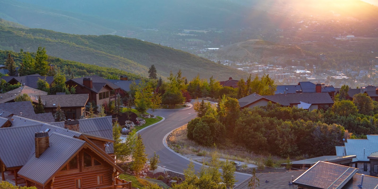 Scenic view of a mountain town with quaint houses surrounded by vibrant trees, showcasing natural beauty and tranquility.