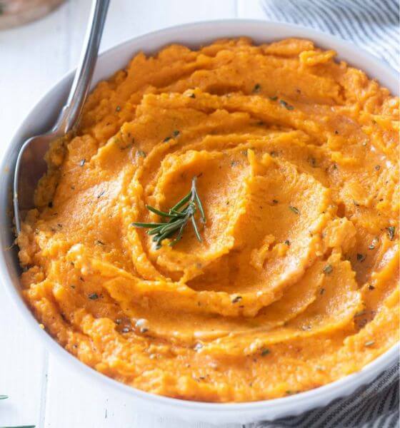 Mashed sweet potatoes in white bowl with spoon