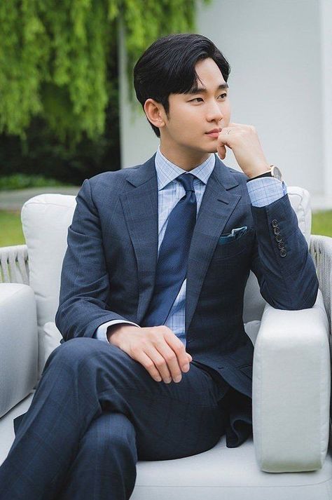 This  contain Kim Soo Hyun  in a suit sitting on a white chair with his hand under his chin