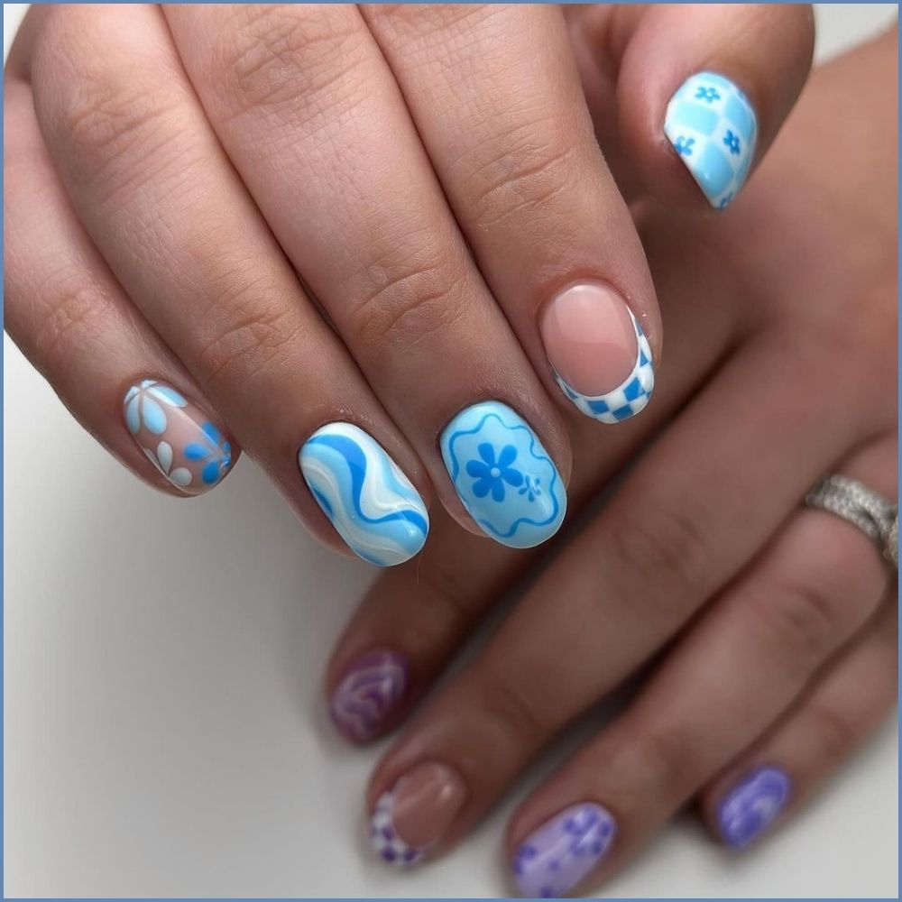 Close up of hands with flowered designed blue nails having Checkered Pattern and Floral Mix