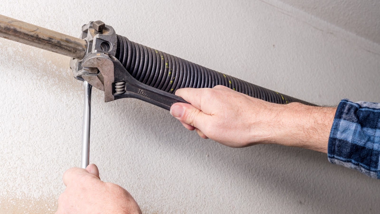 Technician adjusting garage door spring during repair.
