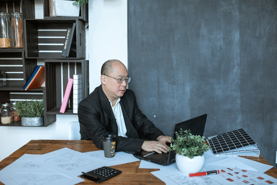 man in black suit jacket sitting in front of a laptop